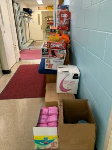 Image of a hallway with stacks of boxes filled non-perishable food items and toiletry items.